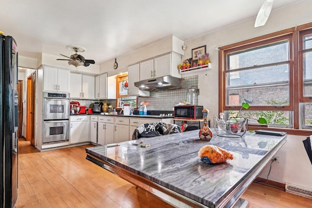 626 E 90th St, Chicago, IL 60619 - kitchen featuring black appliances, under cabinet range hood, light wood finished floors, white cabinetry, and decorative backsplash