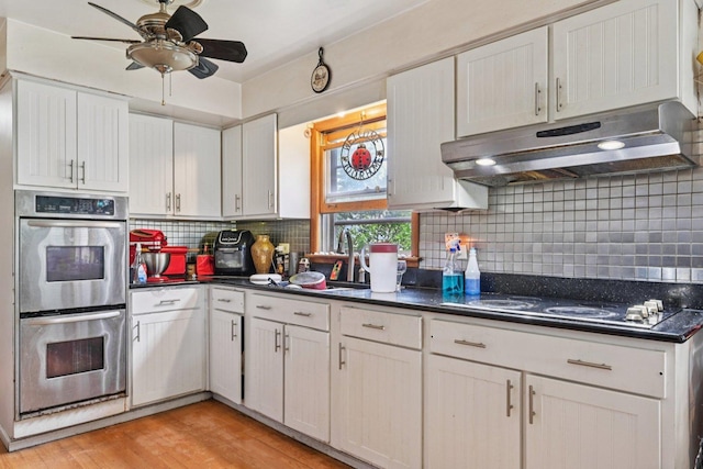 626 E 90th St, Chicago, IL 60619 - kitchen with stainless steel double oven, black electric stovetop, under cabinet range hood, dark countertops, and ceiling fan