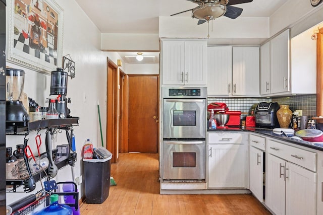 626 E 90th St, Chicago, IL 60619 - kitchen featuring stainless steel double oven, a ceiling fan, dark countertops, light wood-style flooring, and backsplash