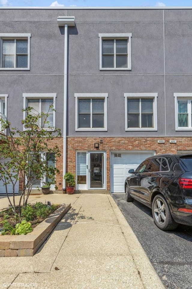 49 W 15th St Unit D, Chicago, IL 60605 - view of front facade featuring a garage, driveway, and stucco siding