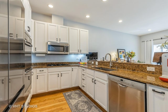 49 W 15th St Unit D, Chicago, IL 60605 - kitchen featuring appliances with stainless steel finishes, light wood finished floors, dark stone counters, white cabinetry, and recessed lighting
