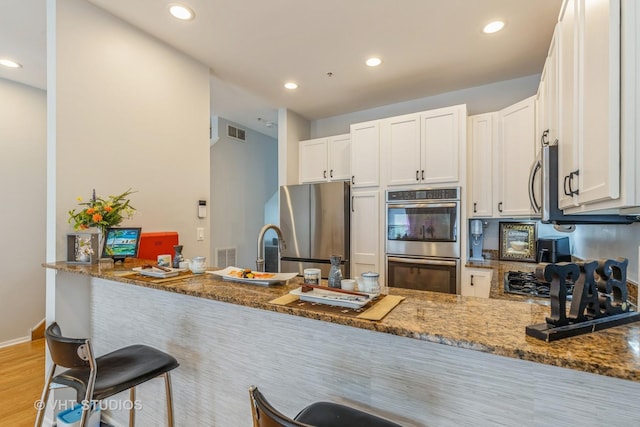 49 W 15th St Unit D, Chicago, IL 60605 - kitchen with appliances with stainless steel finishes, dark stone countertops, recessed lighting, light wood-type flooring, and white cabinets