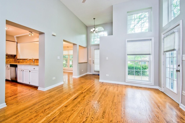 2015 N Silver Lake Rd Unit 1, Arlington Heights, IL 60004 - unfurnished living room featuring a towering ceiling, light wood-style flooring, a chandelier, and a ceiling fan