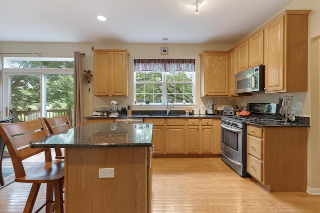 910 Angle Tarn Dr, West Dundee, IL 60118 - kitchen with appliances with stainless steel finishes, light wood finished floors, a breakfast bar, a center island, and dark stone counters