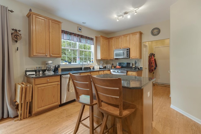 910 Angle Tarn Dr, West Dundee, IL 60118 - kitchen featuring appliances with stainless steel finishes, radiator heating unit, light wood finished floors, a kitchen island, and a breakfast bar area