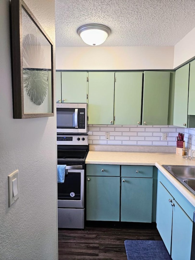 1166 Pomona Dr, Champaign, IL 61822 - kitchen featuring appliances with stainless steel finishes, a textured ceiling, dark wood-style floors, backsplash, and light countertops