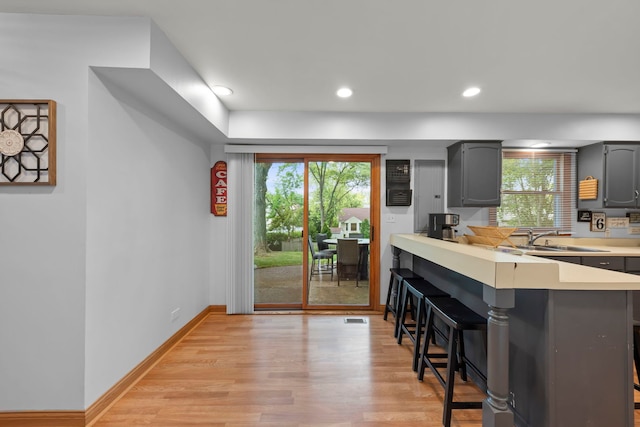 573 Surryse Rd, Lake Zurich, IL 60047 - kitchen with a breakfast bar area, light countertops, a peninsula, gray cabinets, and healthy amount of natural light
