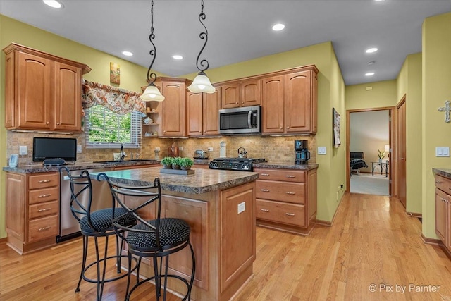 3720 Cypress Dr, Spring Grove, IL 60081 - kitchen with stainless steel microwave, dishwasher, a kitchen island, a kitchen breakfast bar, and light wood-style flooring