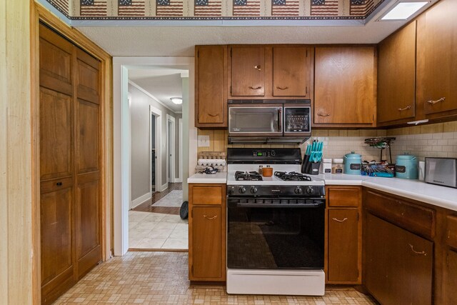 103 Taylor Ct, Catlin, IL 61817 - kitchen with gas stove, backsplash, light countertops, and brown cabinets