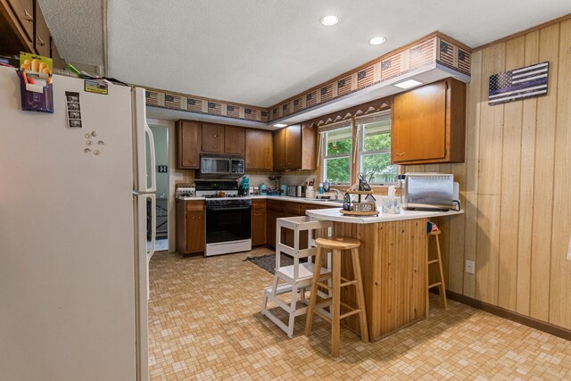 103 Taylor Ct, Catlin, IL 61817 - kitchen featuring white appliances, light floors, wood walls, a peninsula, and light countertops
