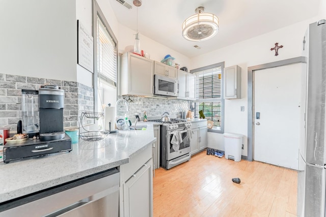 3605 W Cermak Rd, Chicago, IL 60623 - kitchen featuring appliances with stainless steel finishes, tasteful backsplash, light stone countertops, and light wood-style floors