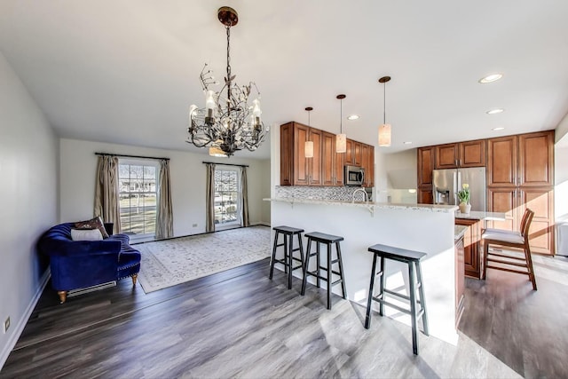 2023 N Shenandoah Dr, Arlington Heights, IL 60004 - kitchen featuring stainless steel appliances, a chandelier, a peninsula, a breakfast bar area, and wood finished floors