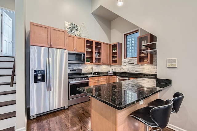 1622 W Ontario St Unit 1E, Chicago, IL 60622 - kitchen with stainless steel appliances, a peninsula, decorative backsplash, glass insert cabinets, and a breakfast bar area