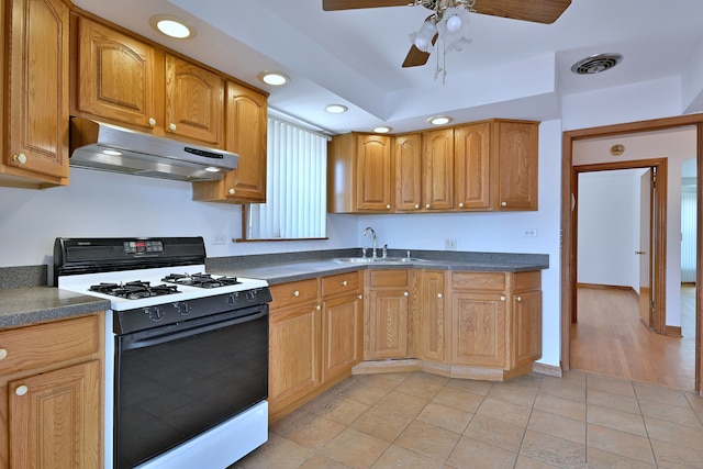 5010 N Merrimac Ave, Chicago, IL 60630 - kitchen featuring gas range oven, under cabinet range hood, dark countertops, a ceiling fan, and light tile patterned flooring