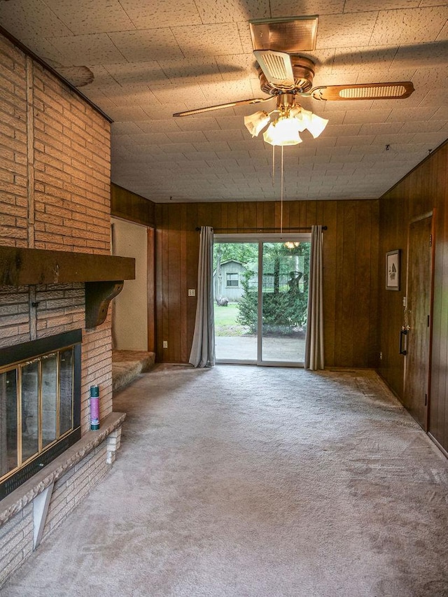 110 Hickory, Villa Grove, IL 61956 - unfurnished living room featuring wood walls, carpet flooring, a ceiling fan, and a fireplace