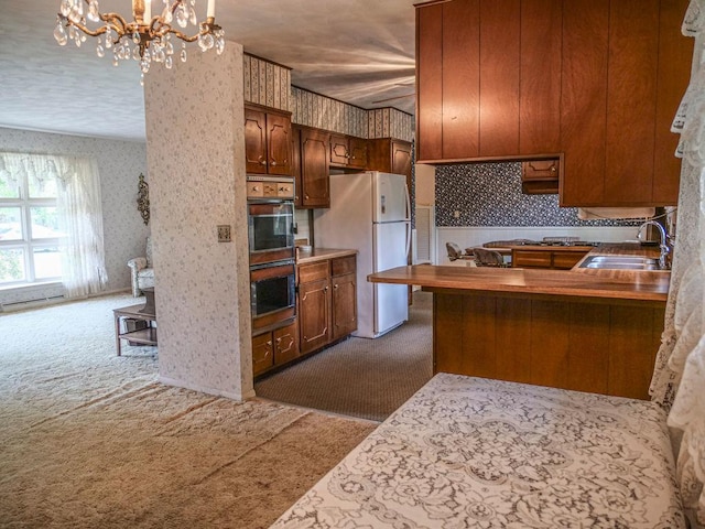 110 Hickory, Villa Grove, IL 61956 - kitchen featuring dark colored carpet, freestanding refrigerator, wallpapered walls, double oven, and a chandelier