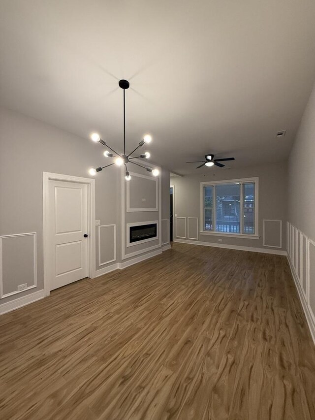 7130 S Morgan St, Chicago, IL 60621 - unfurnished living room with wood finished floors, a ceiling fan, a decorative wall, a chandelier, and a glass covered fireplace