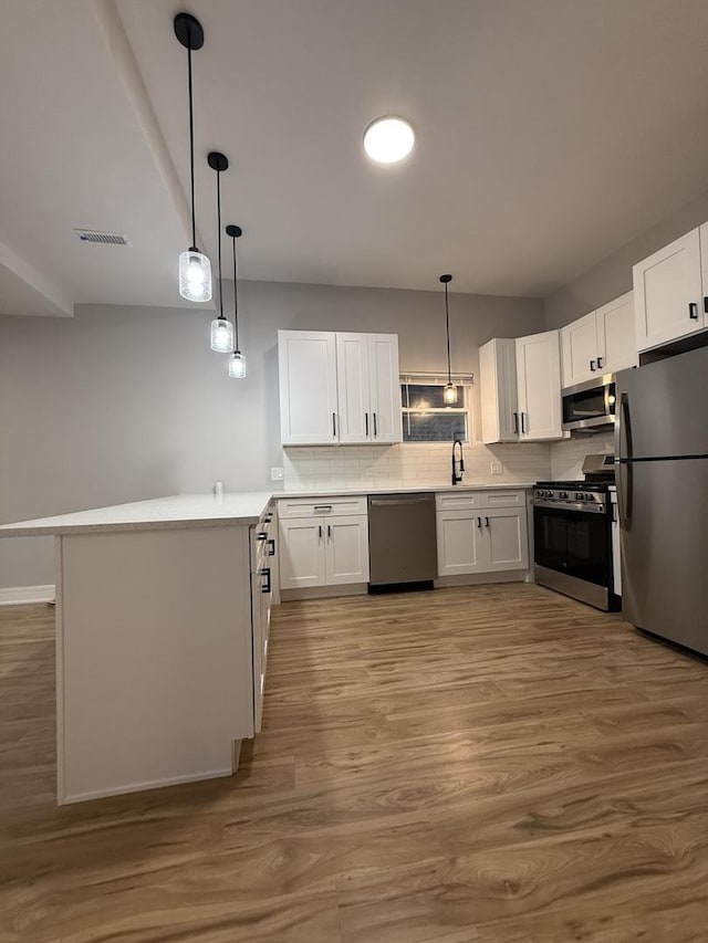 7130 S Morgan St, Chicago, IL 60621 - kitchen with appliances with stainless steel finishes, a peninsula, white cabinetry, wood finished floors, and decorative backsplash