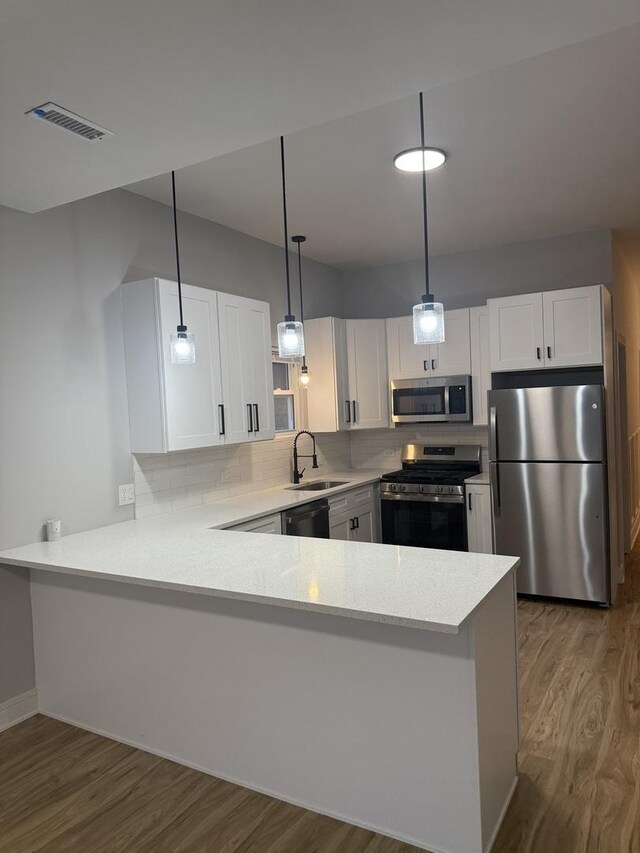 7130 S Morgan St, Chicago, IL 60621 - kitchen with stainless steel appliances, wood finished floors, a peninsula, and light countertops