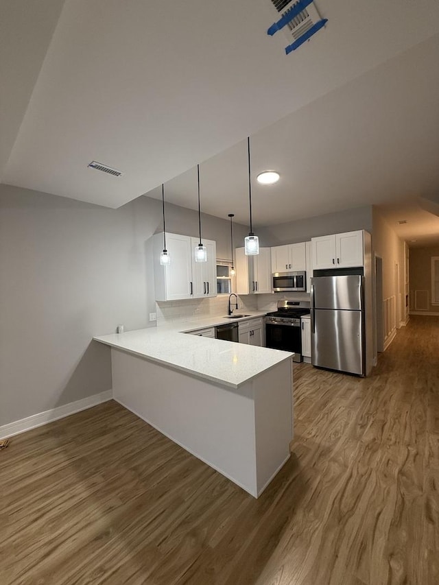 7130 S Morgan St, Chicago, IL 60621 - kitchen with appliances with stainless steel finishes, a peninsula, wood finished floors, white cabinetry, and light countertops