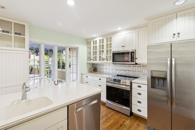 3921 Franklin Ave, Western Springs, IL 60558 - kitchen featuring appliances with stainless steel finishes, light countertops, decorative backsplash, light wood-type flooring, and glass insert cabinets