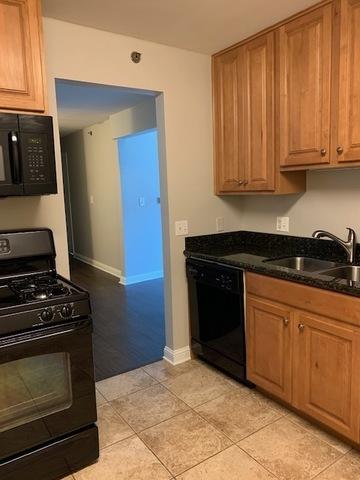 1919 S Wolf Rd Unit 1-322, Hillside, IL 60162 - kitchen featuring black appliances, light tile patterned flooring, dark stone countertops, and brown cabinetry