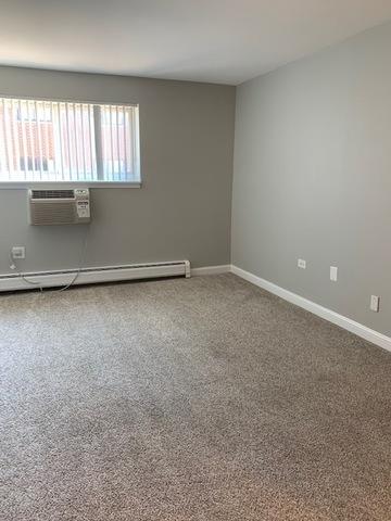 1919 S Wolf Rd Unit 1-322, Hillside, IL 60162 - empty room featuring a baseboard radiator, an AC wall unit, and carpet