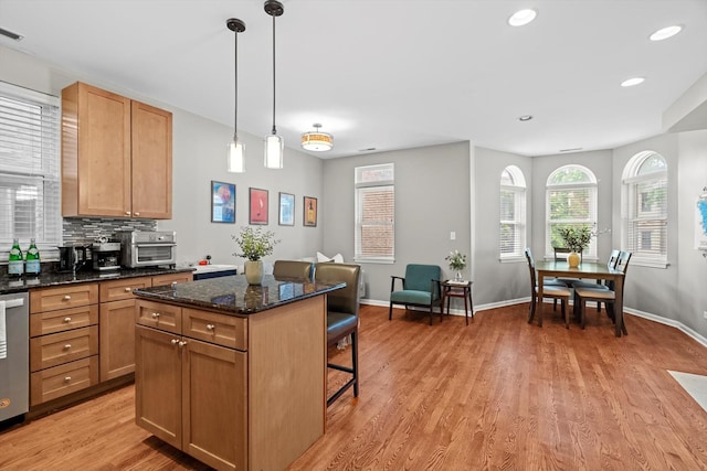 1955 W Melrose St Unit 2, Chicago, IL 60657 - kitchen with a kitchen bar, a kitchen island, decorative backsplash, light wood-style floors, and hanging light fixtures
