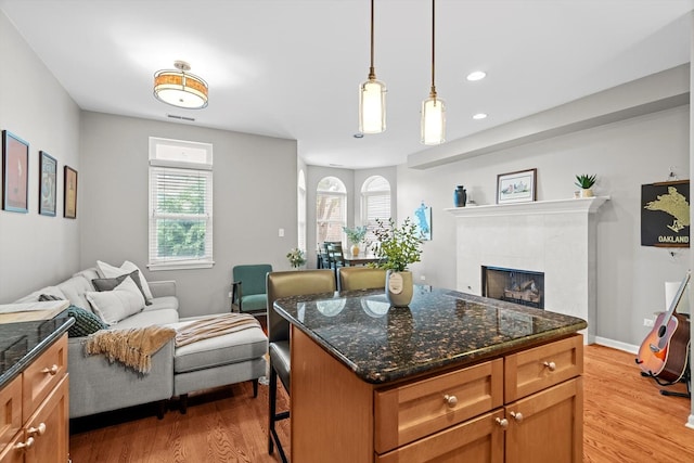 1955 W Melrose St Unit 2, Chicago, IL 60657 - kitchen featuring open floor plan, light wood-type flooring, a tiled fireplace, brown cabinetry, and recessed lighting