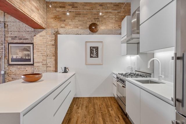 1017 W Washington Blvd Unit 2H, Chicago, IL 60607 - kitchen with wall chimney exhaust hood, high end range, modern cabinets, brick wall, and wood finished floors