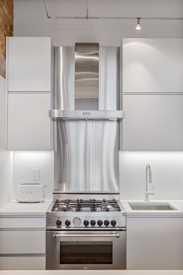 1017 W Washington Blvd Unit 2H, Chicago, IL 60607 - kitchen with high end stove, wall chimney exhaust hood, light countertops, and white cabinets