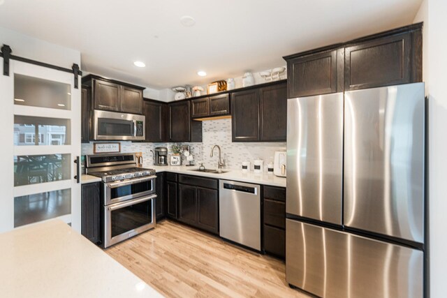 1113 Sapphire Ln, Pingree Grove, IL 60140 - kitchen featuring appliances with stainless steel finishes, dark brown cabinets, light countertops, light wood-style flooring, and tasteful backsplash