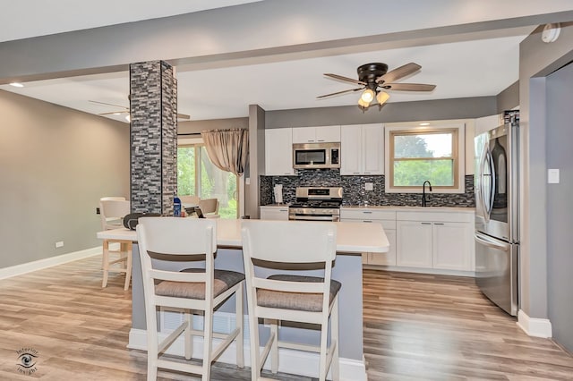 17242 Odell Ave, Tinley Park, IL 60477 - kitchen with appliances with stainless steel finishes, light wood finished floors, a breakfast bar, backsplash, and white cabinets