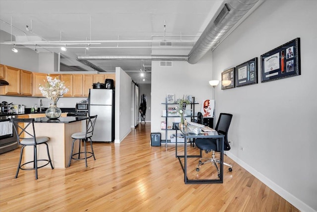 500 S Clinton St Unit 527, Chicago, IL 60607 - kitchen featuring freestanding refrigerator, light brown cabinetry, dark countertops, a kitchen breakfast bar, and a center island