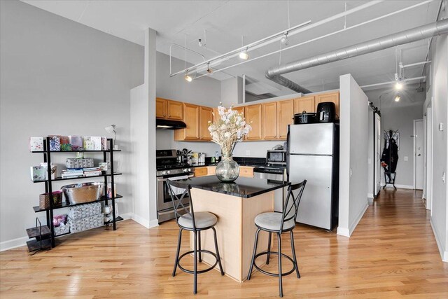500 S Clinton St Unit 527, Chicago, IL 60607 - kitchen with stainless steel appliances, under cabinet range hood, light wood-style floors, light brown cabinetry, and dark countertops