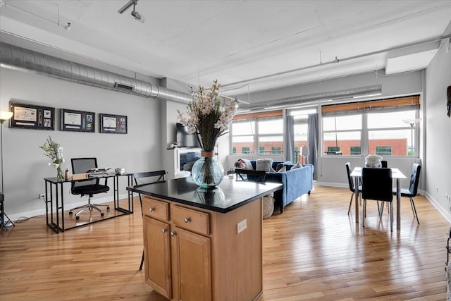 500 S Clinton St Unit 527, Chicago, IL 60607 - kitchen with light wood finished floors, a center island, dark countertops, an office area, and brown cabinets