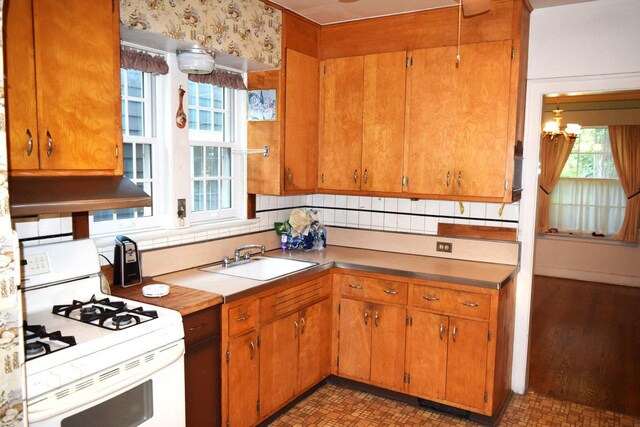 2008 Mcdaniel Ave, Evanston, IL 60201 - kitchen featuring white range with gas cooktop, exhaust hood, a chandelier, and brown cabinetry