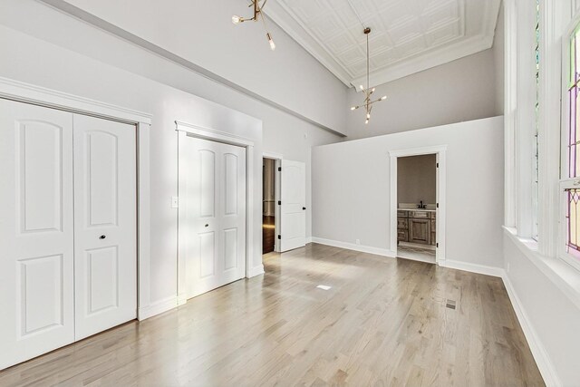 200 W Crawford St, Peotone, IL 60468 - unfurnished bedroom with light wood-style floors, a towering ceiling, ensuite bath, and a chandelier