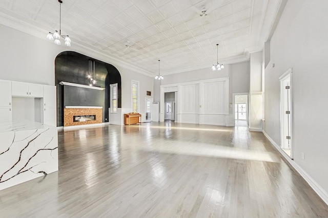 200 W Crawford St, Peotone, IL 60468 - unfurnished living room featuring arched walkways, a high ceiling, ornamental molding, healthy amount of natural light, and light wood-type flooring