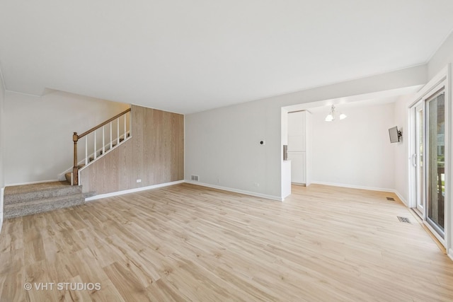 2733 Weeping Willow Dr Unit 26-C, Lisle, IL 60532 - unfurnished living room featuring stairway, a chandelier, light wood-style flooring, and wooden walls