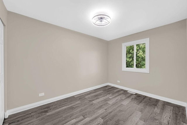 spare room featuring dark wood-type flooring and baseboards