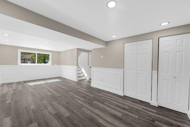 basement with stairway, dark wood finished floors, wainscoting, recessed lighting, and a decorative wall