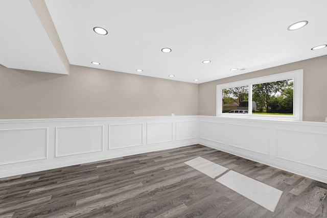 spare room featuring recessed lighting, a wainscoted wall, and dark wood-type flooring