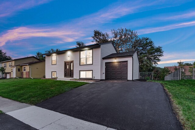 raised ranch featuring a garage and asphalt driveway