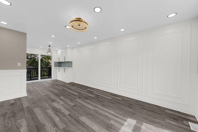 unfurnished living room with a decorative wall, dark wood-style floors, recessed lighting, and wainscoting