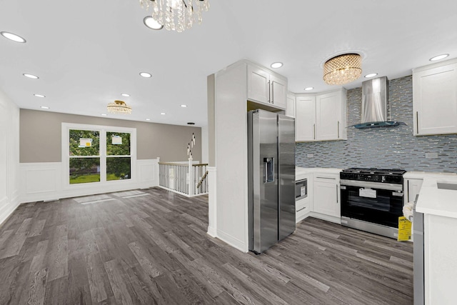 kitchen featuring wall chimney exhaust hood, stainless steel fridge, gas stove, a chandelier, and dark wood-style floors