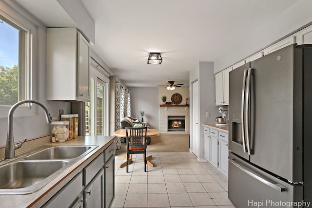 2184 N Masters Ln, Lake Villa, IL 60046 - kitchen featuring stainless steel fridge, a brick fireplace, a ceiling fan, light tile patterned floors, and white cabinetry