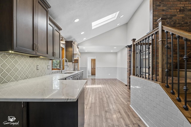 509 Apollo Dr, Joliet, IL 60435 - kitchen featuring vaulted ceiling, a skylight, light wood finished floors, light stone countertops, and dark brown cabinets
