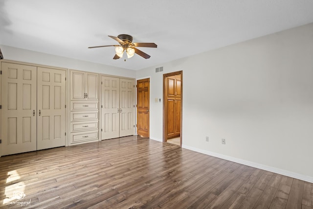 509 Apollo Dr, Joliet, IL 60435 - unfurnished bedroom featuring two closets, wood finished floors, and ceiling fan