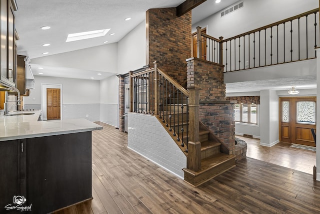509 Apollo Dr, Joliet, IL 60435 - unfurnished living room featuring high vaulted ceiling, stairs, wood finished floors, a skylight, and wainscoting